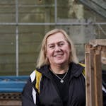 Elderly woman smiling while working inside a greenhouse