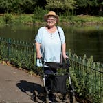 Senior woman with walking frame enjoying a sunny day by the pond.